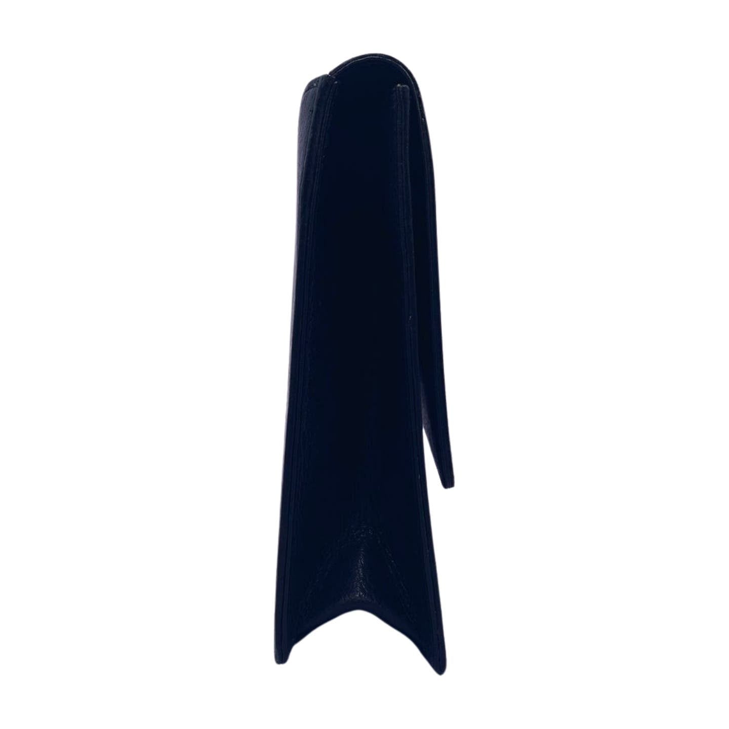 Side view of a dark, triangular-shaped standing object, possibly an original Valentino Garavani Valentino Black Leather Clutch or a slim folder with a smooth surface. The object’s edges are sharp, and it casts a slight shadow to the right.