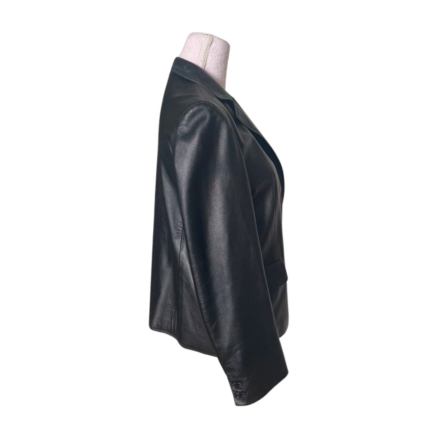 Side view of a Vintage Balmain Black Leather Blazer displayed on a neutral-colored dress form. The blazer features a single-breasted design with a notch lapel and polyester lining. The image is set against a white background, highlighting the sleek tailoring and emphasizing the importance of professional cleaning.