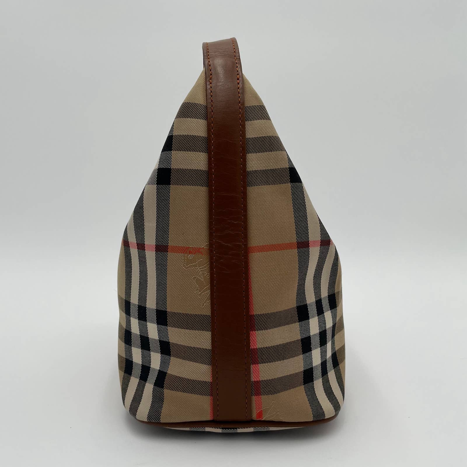 A side view of a beige plaid canvas bag with leather trim in black, white, and red stripes, featuring a brown leather strip running vertically along the center. The zip top bag is set against a plain white background, echoing the charm of a Burberry Vintage House Check Bag by Burberry.