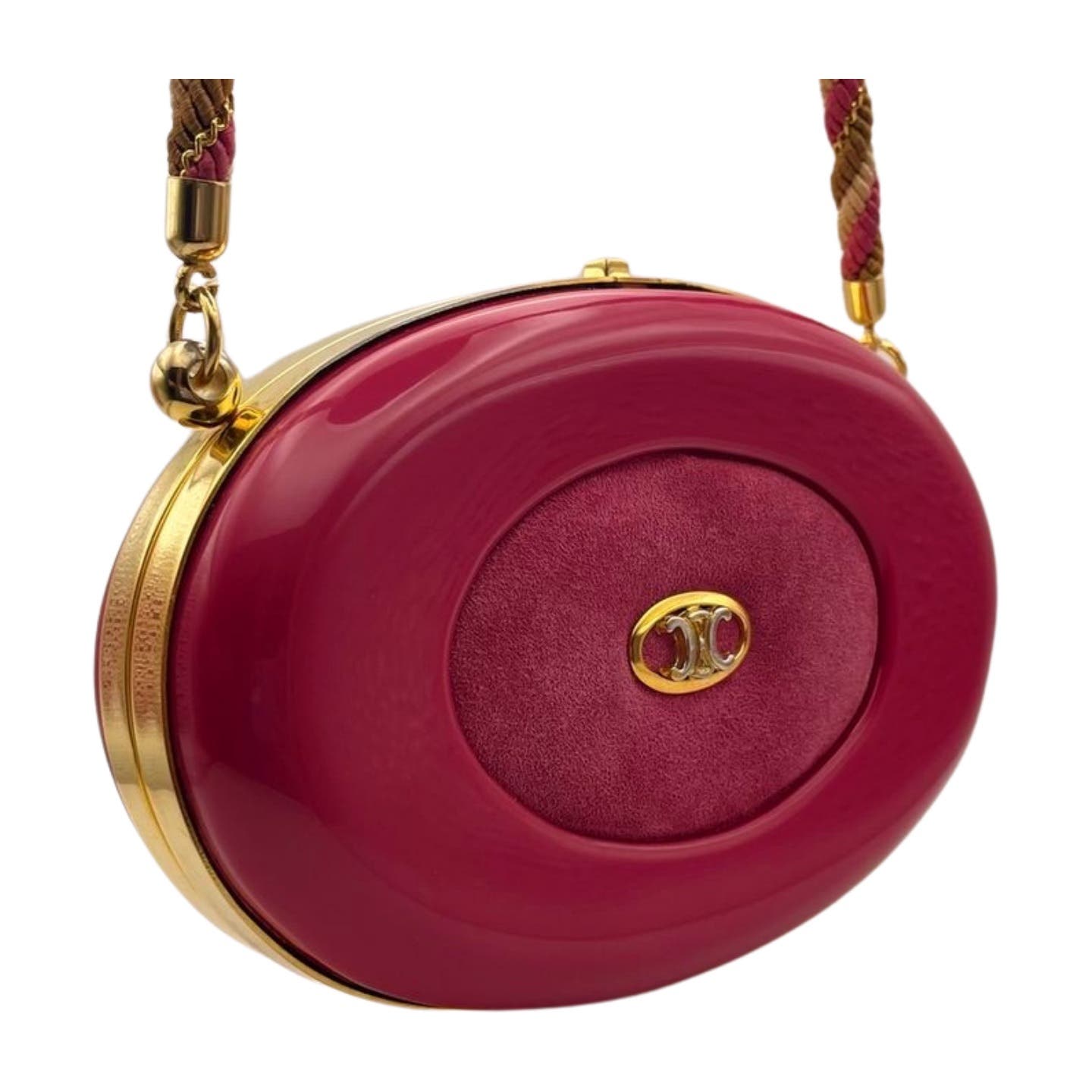 A small, round, maroon Vintage Celine Hard Shell Bag with gold accents featuring a central suede patch and a gold clasp with a pink gemstone. The strap is braided with brown and maroon colors. This vintage Celine piece boasts an acrylic and suede exterior that adds a timeless charm to any outfit.