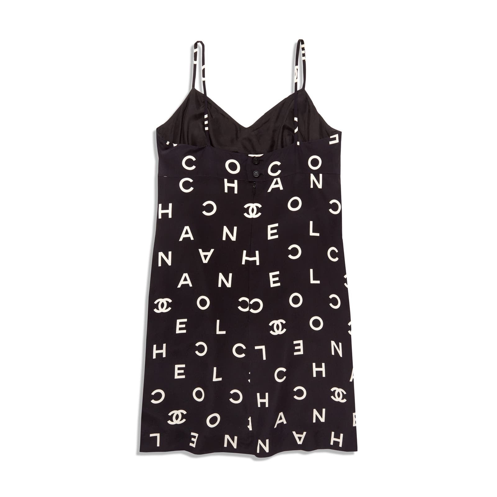 A black sleeveless **Vintage Chanel 1997 Runway Alpha Logo Coco Print Slip Dress and Jacket Set** with thin straps, adorned with various white letters forming the words "COCO" and "CHANEL," along with **Chanel**'s iconic interlocking "CC" logo. This piece from the Spring 1997 ready-to-wear collection features a fitted bust and a straight-cut silhouette.